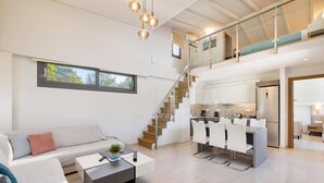 A modern living room with a sofa, coffee table, and a staircase leading to a kitchen area.