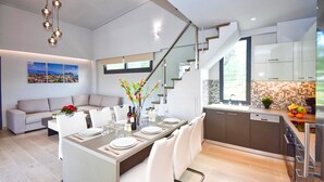 Een moderne keuken met een eetgedeelte, een trap en een woonkamer met een bank en een stadsgezicht schilderij.