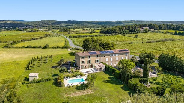A large building with a swimming pool, surrounded by green fields and vineyards. - Villa Les Juliannes by Villa Plus (Azillanet)