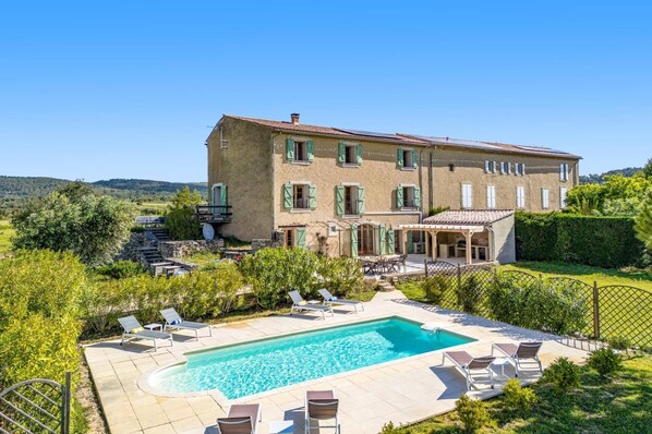 A large two-story house with a swimming pool, outdoor seating, and a view of the countryside. - Villa Les Juliannes by Villa Plus (Azillanet)