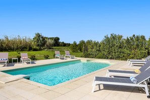 A rectangular pool with clear blue water, surrounded by white lounge chairs and a white table. - Villa Les Juliannes by Villa Plus (Azillanet)