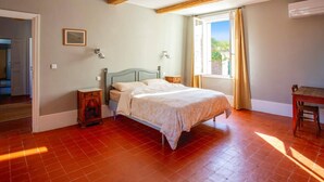 Une chambre à coucher avec un lit, une table de chevet, une fenêtre avec des rideaux et une poutre en bois au plafond.