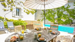 Une table en bois, dressée pour le petit-déjeuner, avec une piscine en arrière-plan.