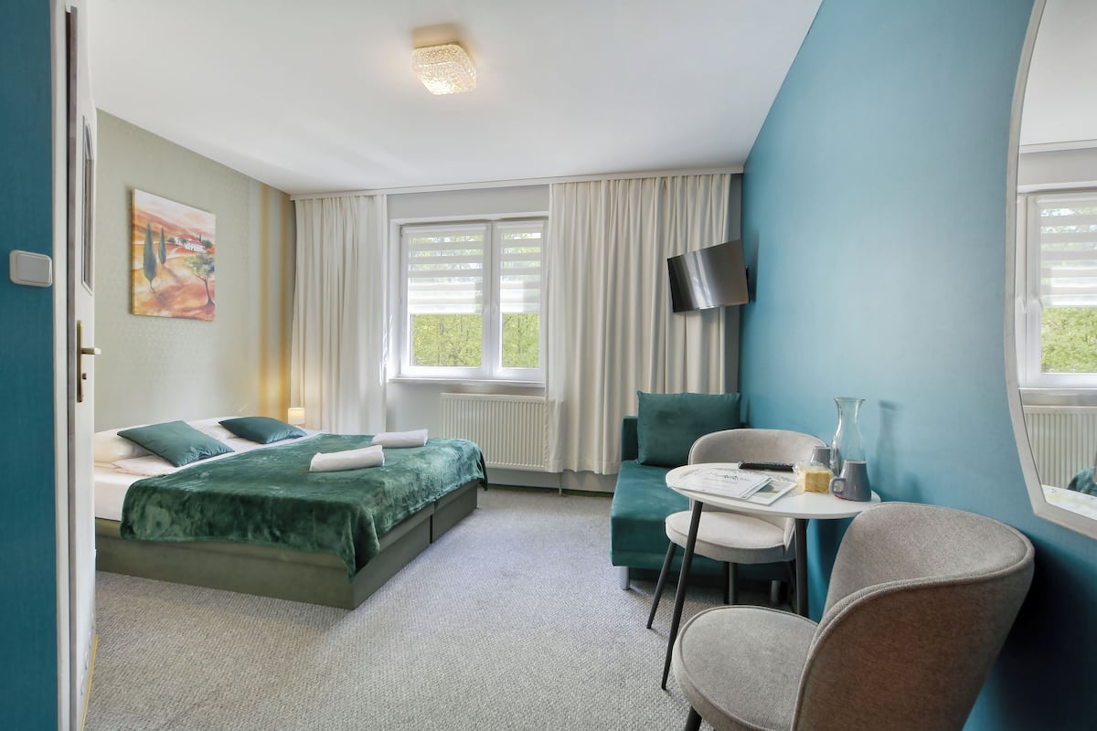 Et hotelværelse med en seng, en sofa, et lille bord og et fjernsyn.