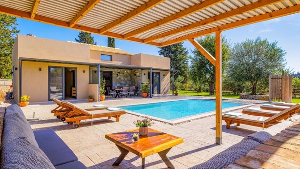 Ein moderner Poolbereich im Freien mit Liegestühlen, einem Holztisch und einer überdachten Lounge-Ecke.