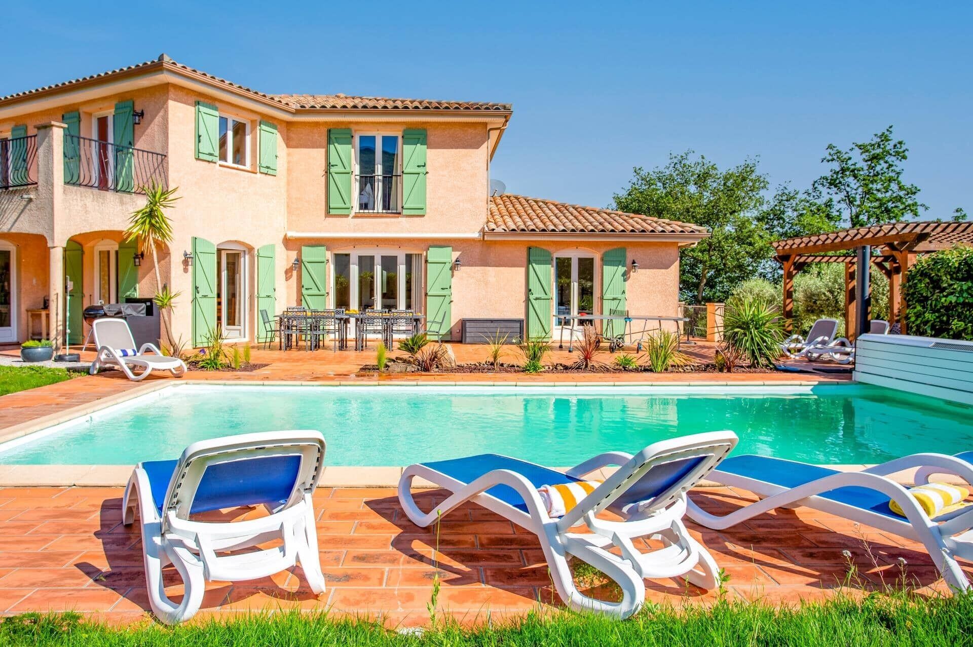 Una casa con piscina, muebles de exterior y una pérgola.