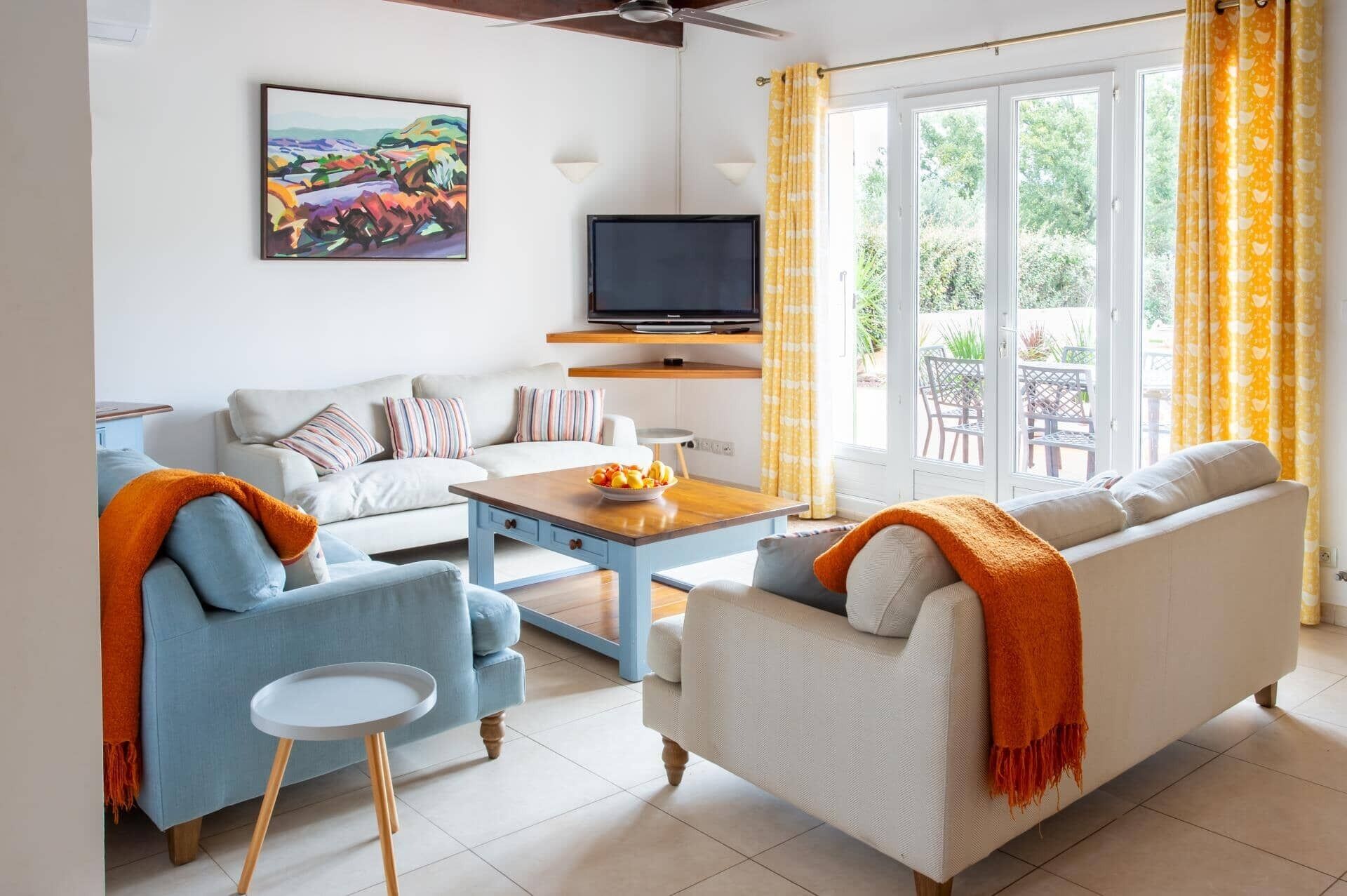 A living room with a sofa, armchairs, a coffee table, a TV, and a painting on the wall.