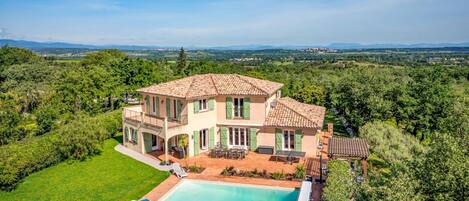 A two-story house with a swimming pool and outdoor seating.