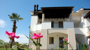 A two-story building with a flat roof, a balcony, and a chimney.