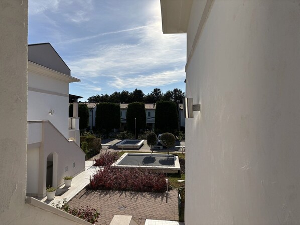 A courtyard with a pool, potted plants, and a clear sky.