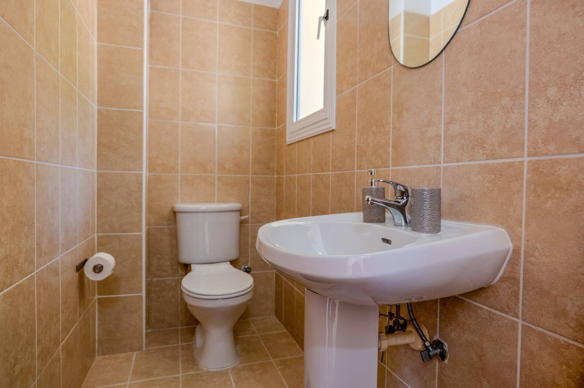 Une salle de bain avec un lavabo blanc, des toilettes et un miroir au mur.