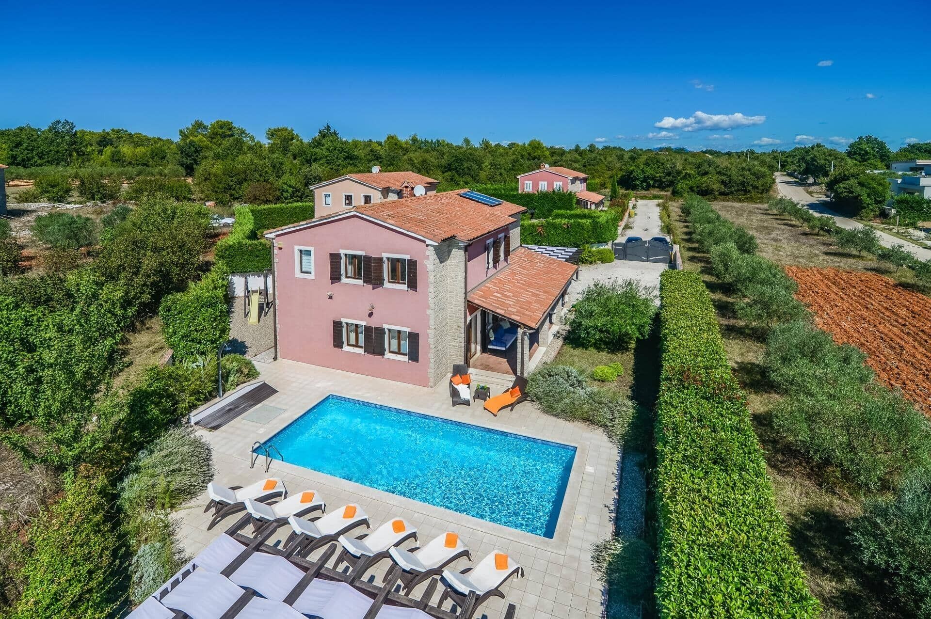 A two-story house with a swimming pool and sun loungers.