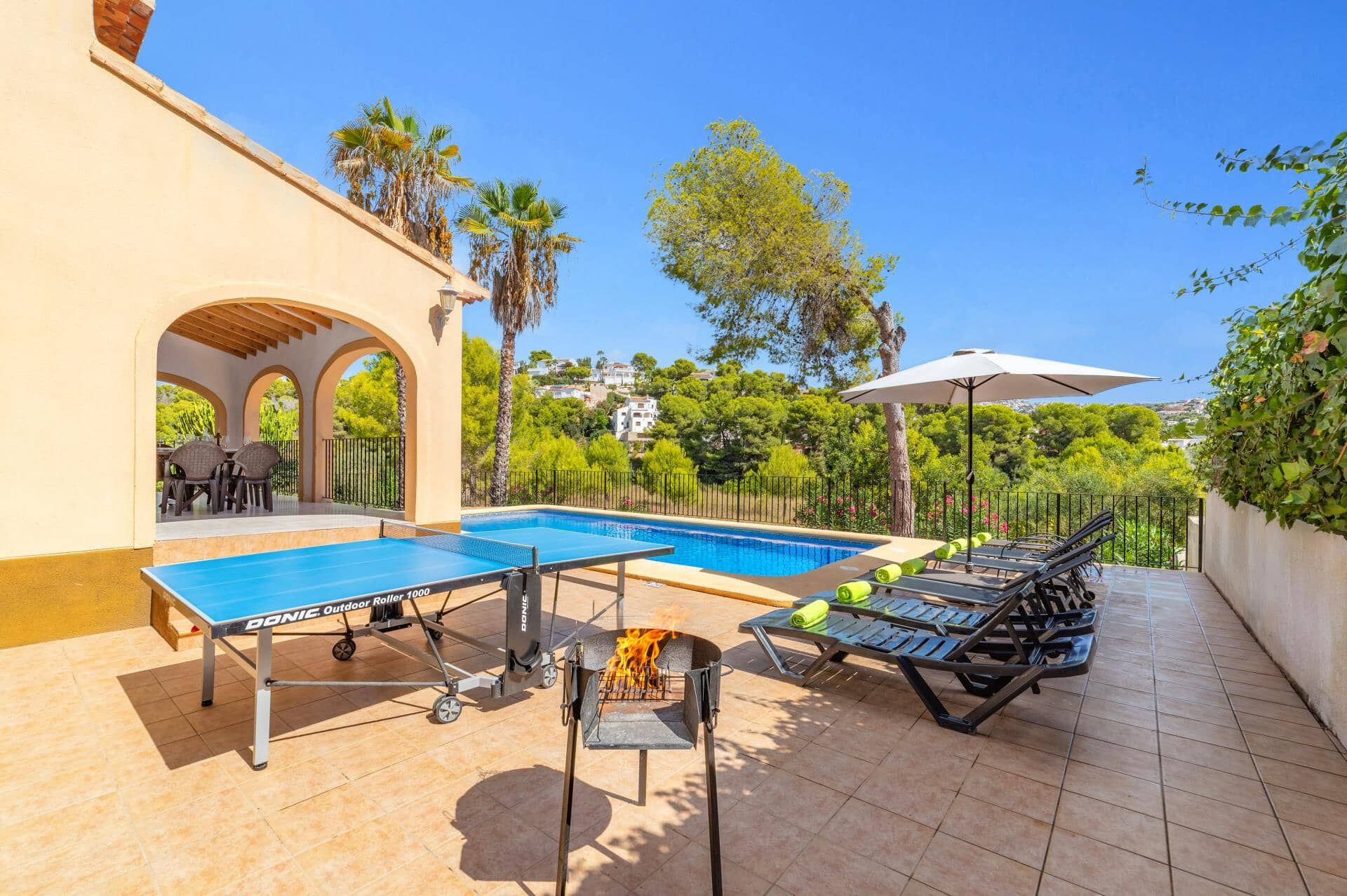 Un espace extérieur avec une piscine, une table de ping-pong, des chaises longues et un barbecue.