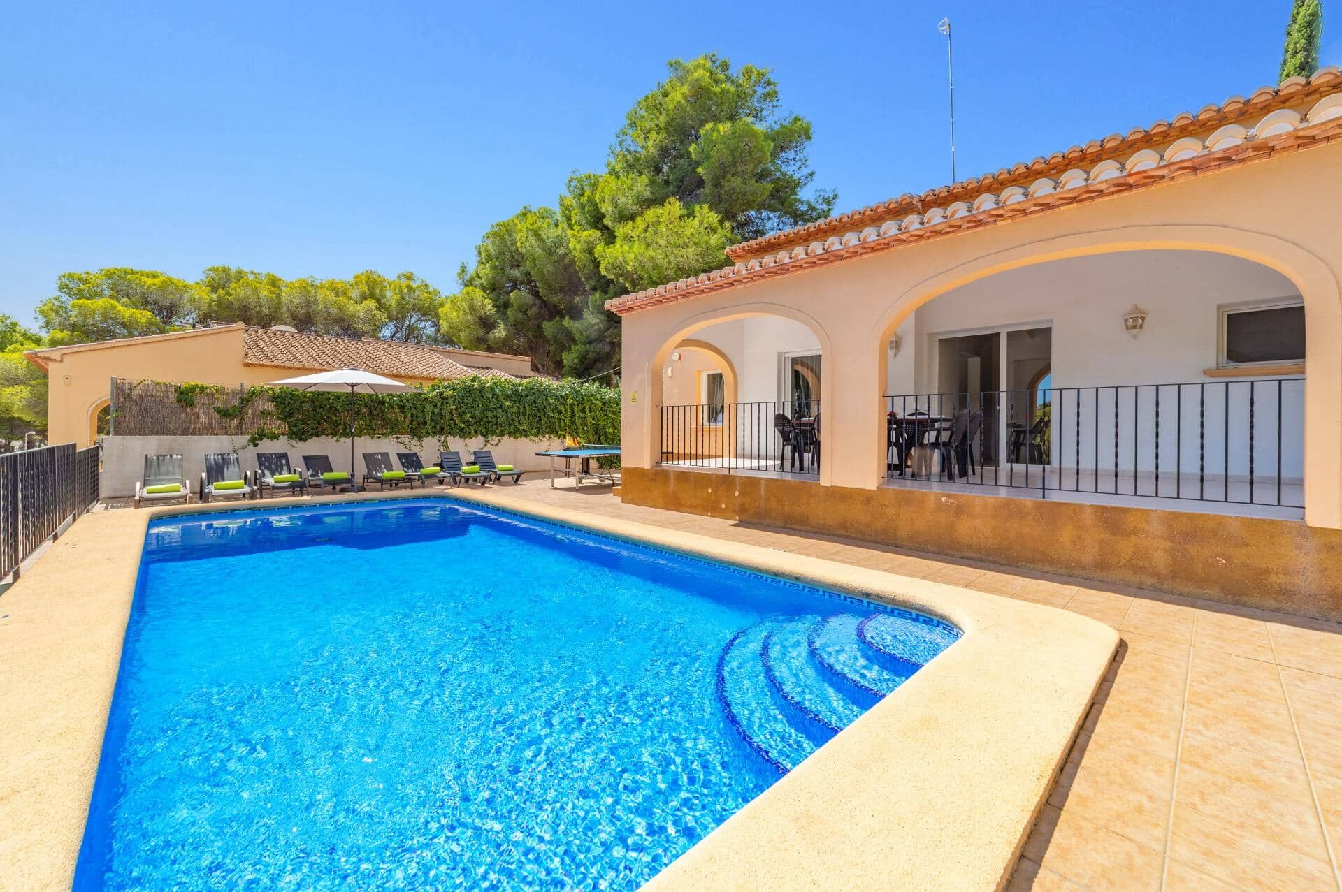 A swimming pool with lounge chairs and a covered patio area.