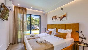 A hotel room with two beds, a large window with curtains, a painting on the wall, and a small table with a lamp. - Villa Manefic by Villa Plus (Malevizi)