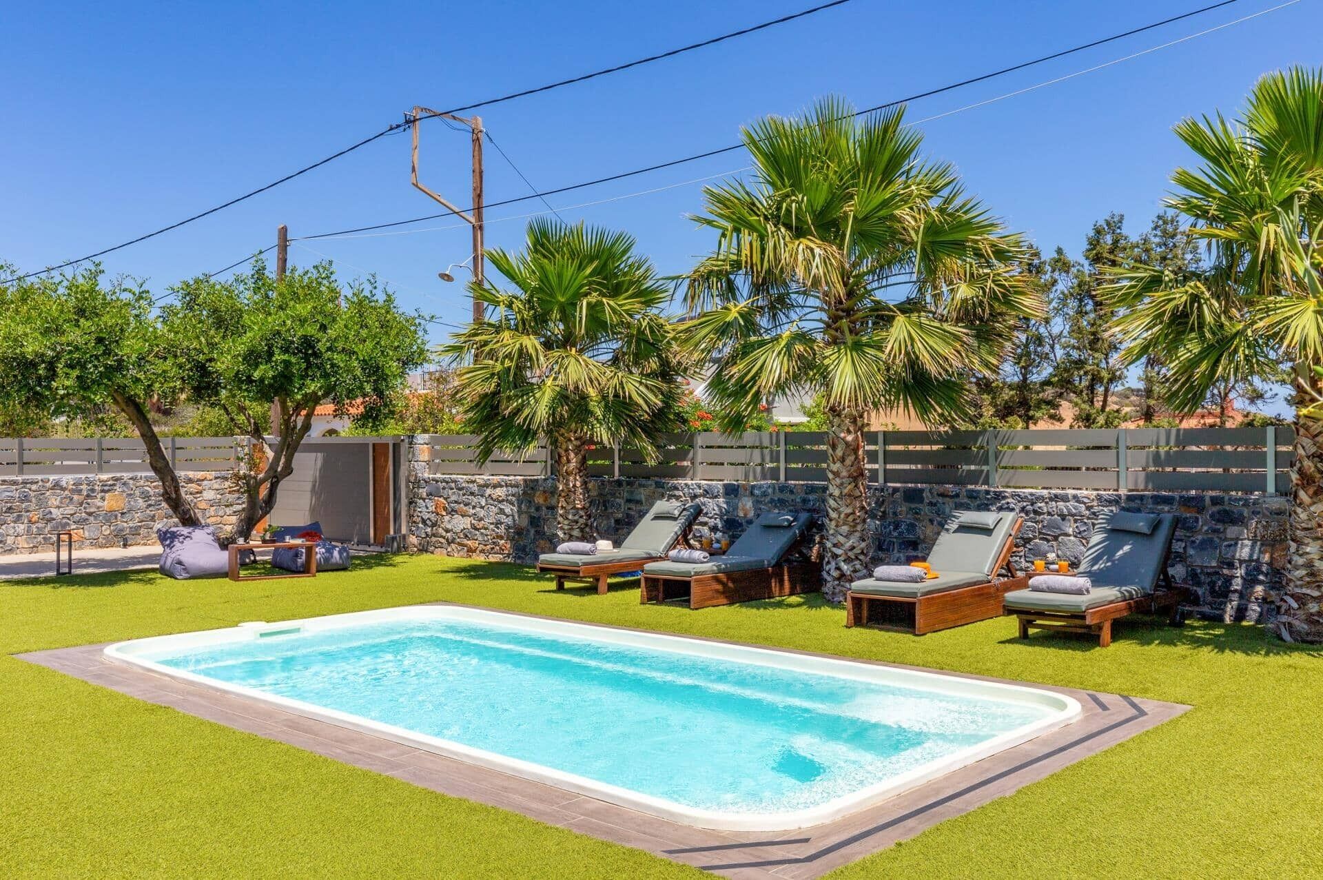 Una piscina con sillones de descanso y palmeras.