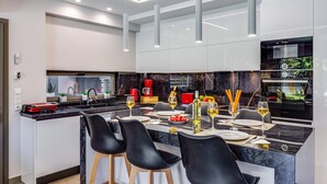 A modern kitchen with a central island, black bar stools, a coffee machine, and a Bosch refrigerator. - Villa Manefic by Villa Plus (Malevizi)