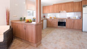 A modern kitchen with wooden cabinets, a built-in oven, and a dishwasher. - Villa Tia Elanor by Villa Plus (Jávea)