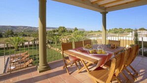 A covered outdoor dining area with a table set for two, surrounded by wooden chairs, a tiled floor, and a view of a hilly landscape. - Villa Tia Elanor by Villa Plus (Jávea)