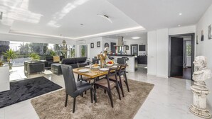 A spacious living area with a dining table, comfortable seating, and a view of the outdoors.