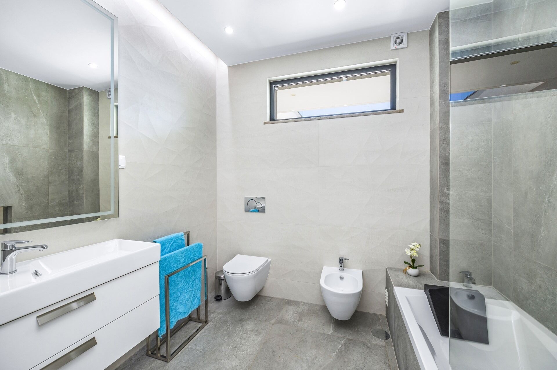 Un baño moderno con un espejo grande, un bidé, un inodoro y una bañera.