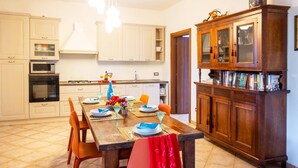A kitchen with white cabinets, a wooden dining table set with plates, glasses, and a fruit bowl.