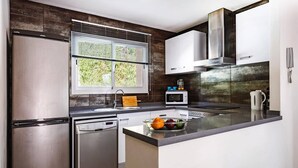 A modern kitchen with stainless steel appliances, a built-in oven, and a large window with blinds. - Villa Pomera Tres by Villa Plus (Beniarbeig)