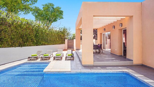 A swimming pool with lounge chairs, a covered patio area, and a view of trees. - Villa Pomera Tres by Villa Plus (Beniarbeig)