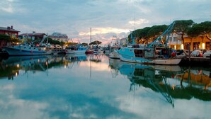 Un puerto deportivo con barcos amarrados, agua tranquila y edificios al fondo.