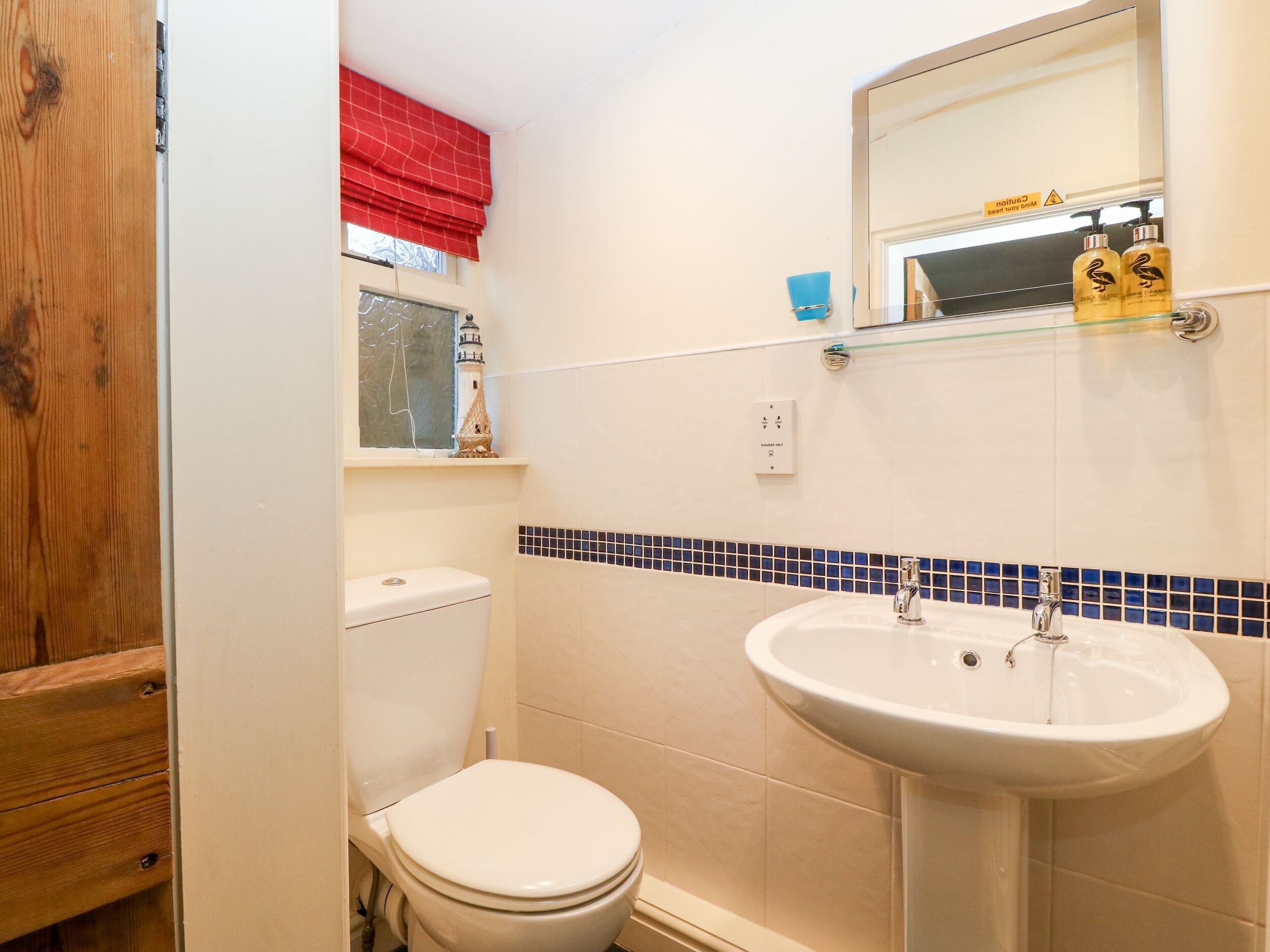 Ein Badezimmer mit Toilette, Waschbecken und einem Fenster mit rotem Vorhang.