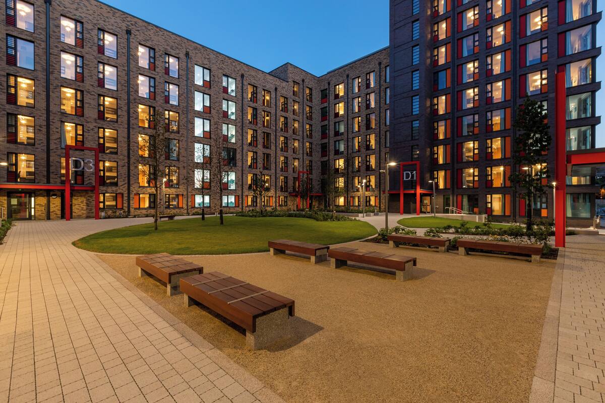Un bâtiment moderne à étages, doté d’espaces extérieurs aménagés pour s’asseoir et d’une cour bien entretenue.