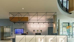 A modern reception desk with a digital display, a waiting area, and a view of the outdoors. - UCD Campus Accommodation (Dublin)