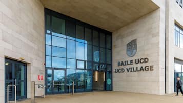 Enter the Baile UCD Village, a modern gateway to University College Dublin's campus, featuring a clear view of the interior through large glass windows.