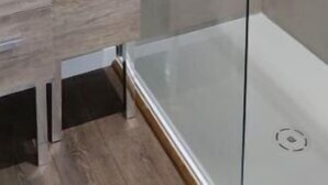 Une salle de bain moderne avec une douche à parois de verre, un meuble en bois et un lavabo blanc.