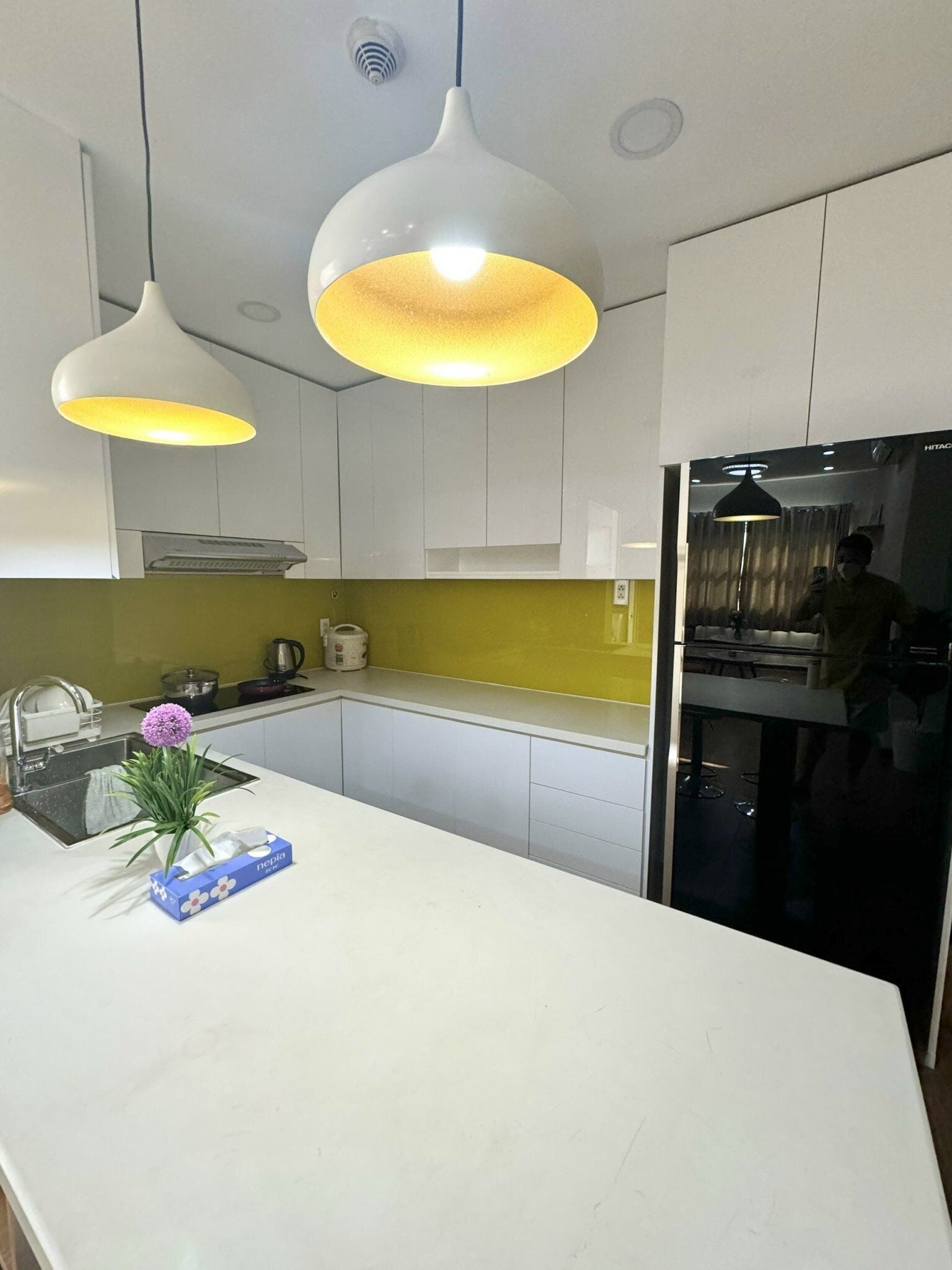 A modern kitchen with white cabinets, a white countertop, and two pendant lights.