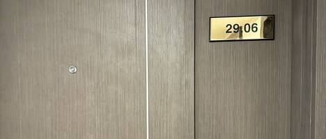 Une porte en bois avec une poignée en métal et un trou de serrure, ainsi qu’une plaque en laiton portant le numéro 29,06.