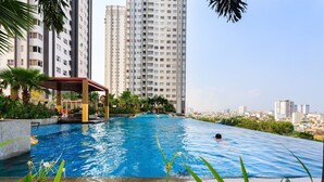 Una piscina en la azotea con vistas a rascacielos y un área de estar cubierta.