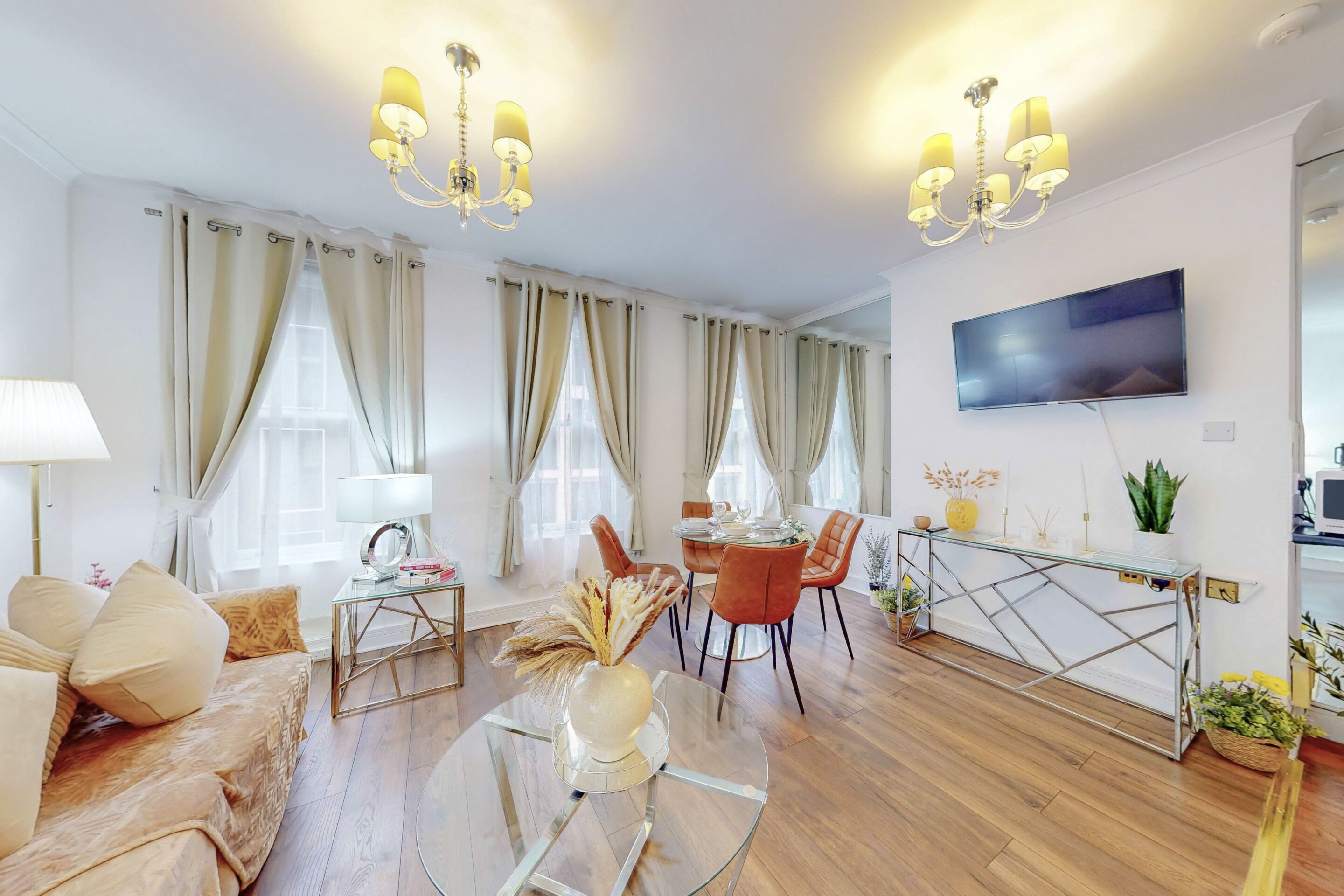 A modern living room with a sofa, coffee table, dining table, chairs, and a TV.