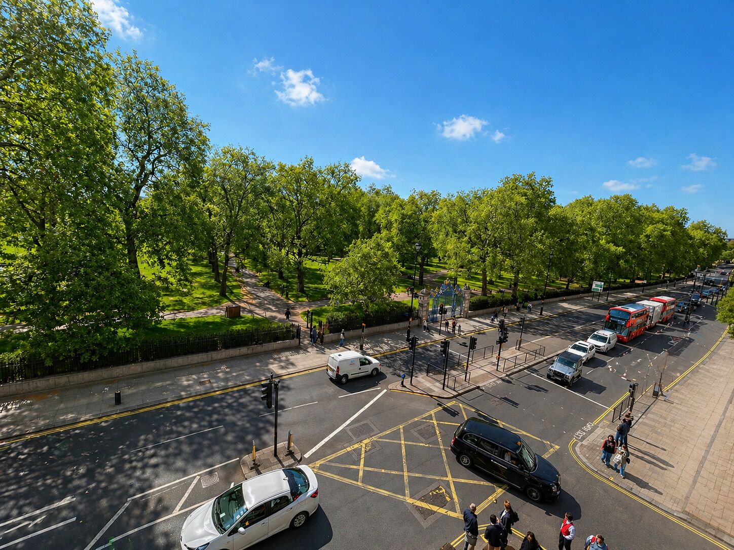 A multi-lane road with vehicles, a pedestrian crossing, and a park with trees.