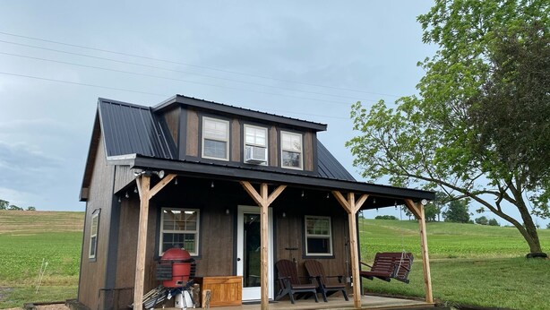 A two-story wooden house with a porch, a red barbecue grill, and outdoor seating. - Pondside Paradise (Singers Glen)
