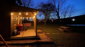A wooden deck with a covered seating area, a barbecue grill, and a picnic table. - Pondside Paradise (Singers Glen)