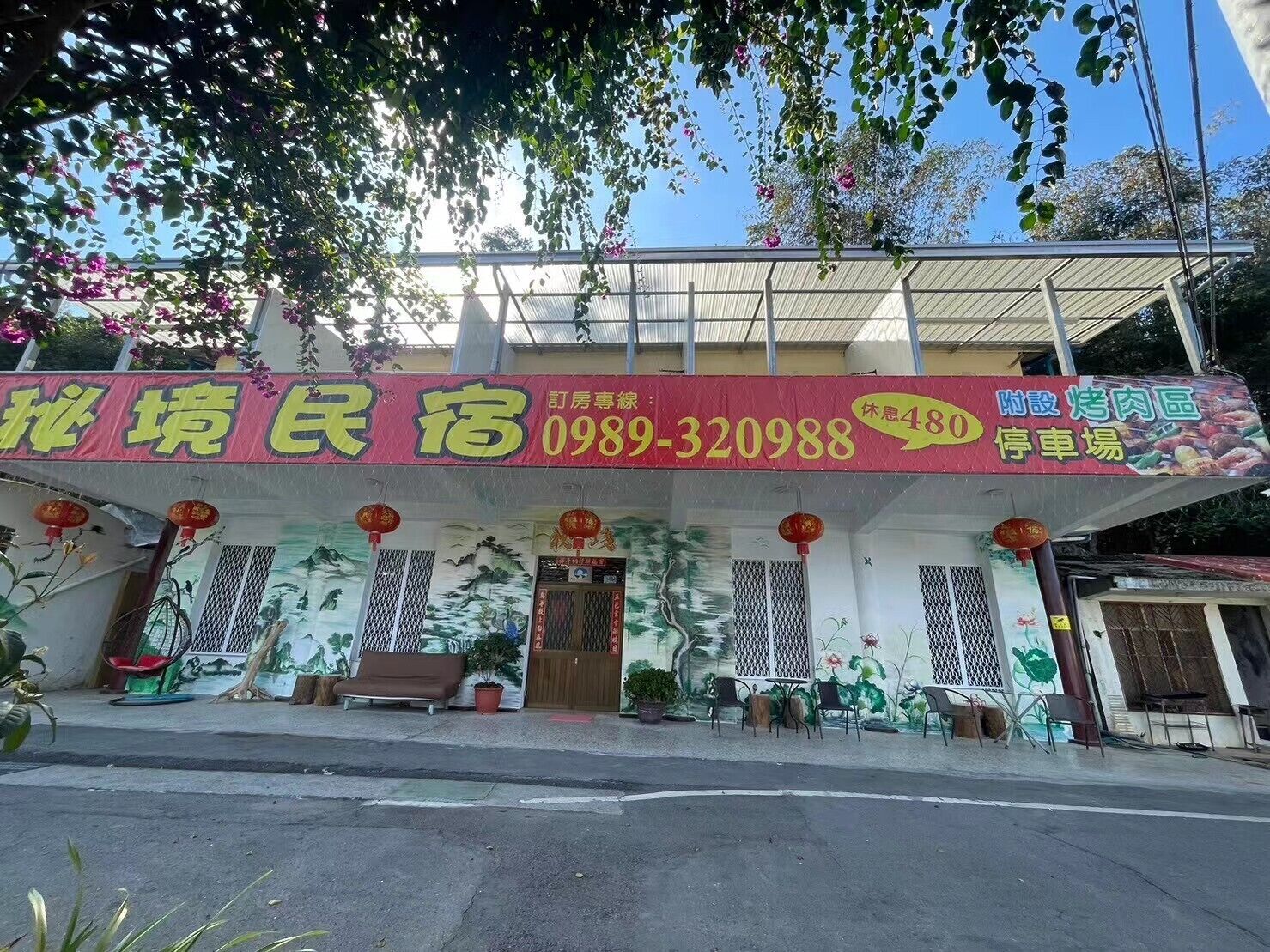 A building with a red and yellow signboard, a covered entrance, and outdoor seating.