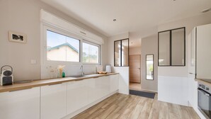 A modern kitchen with a large window, wooden flooring, and white cabinetry. - 300m from the beach, house for 7 with a pool (Lanton)