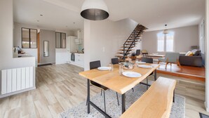 A spacious kitchen with a central island, a dining area with a wooden table and benches, and a staircase leading to an upper level. - 300m from the beach, house for 7 with a pool (Lanton)