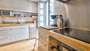 Une cuisine moderne avec des armoires blanches, une hotte de cuisinière en acier inoxydable, un four à micro-ondes et une machine à café.