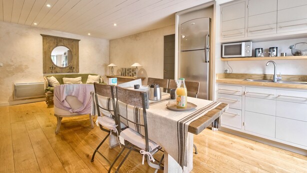 Une cuisine moderne avec une table en bois, des chaises, un réfrigérateur et un four à micro-ondes.