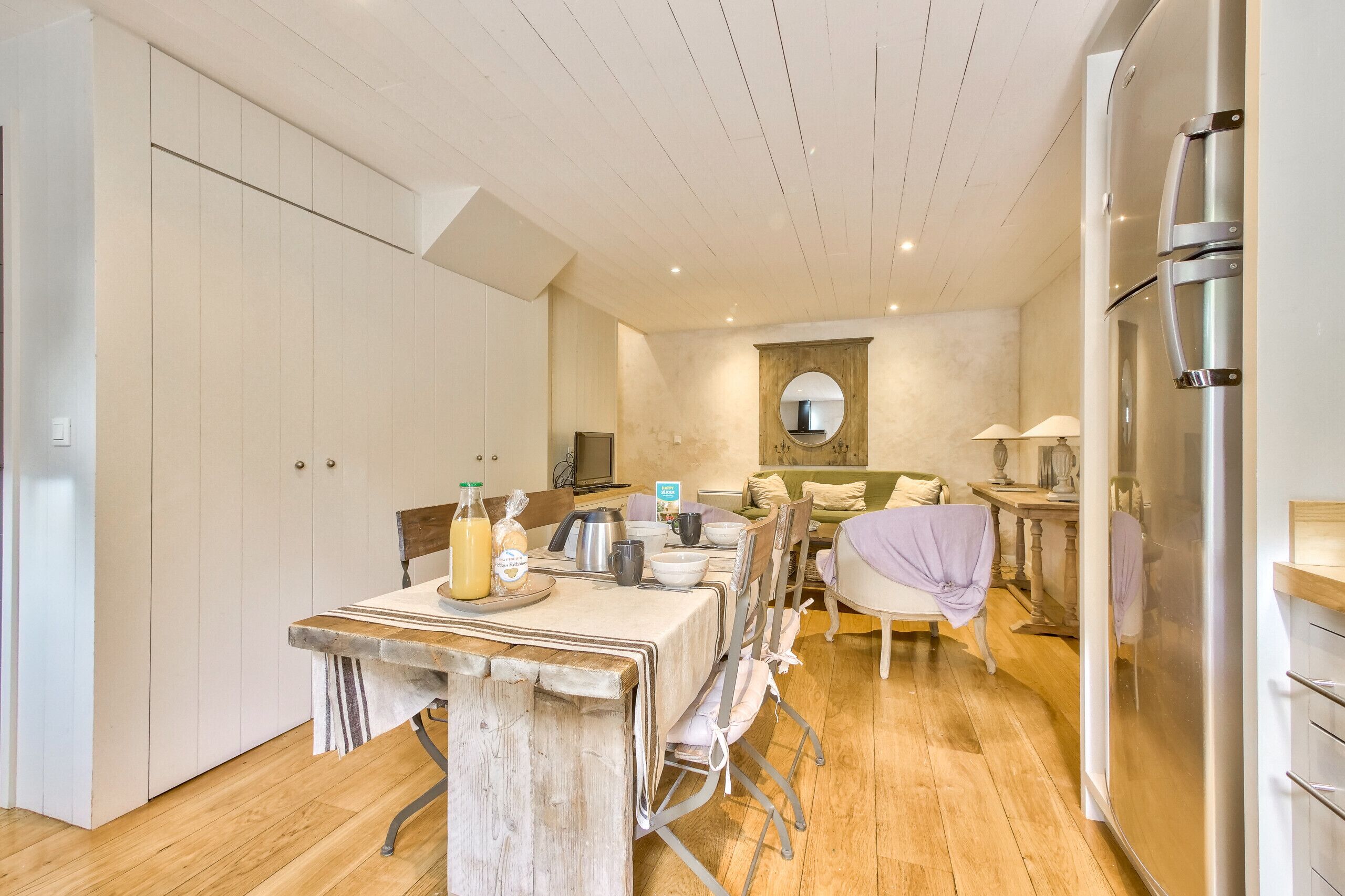A modern kitchen with wooden flooring, a dining table set for four, and a built-in oven.