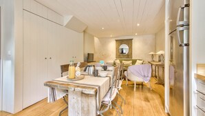 Une cuisine moderne avec un plancher en bois, une table à manger pour quatre personnes et un four encastré.