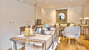 Un coin repas avec une table dressée pour quatre personnes, un téléviseur et un miroir au mur.
