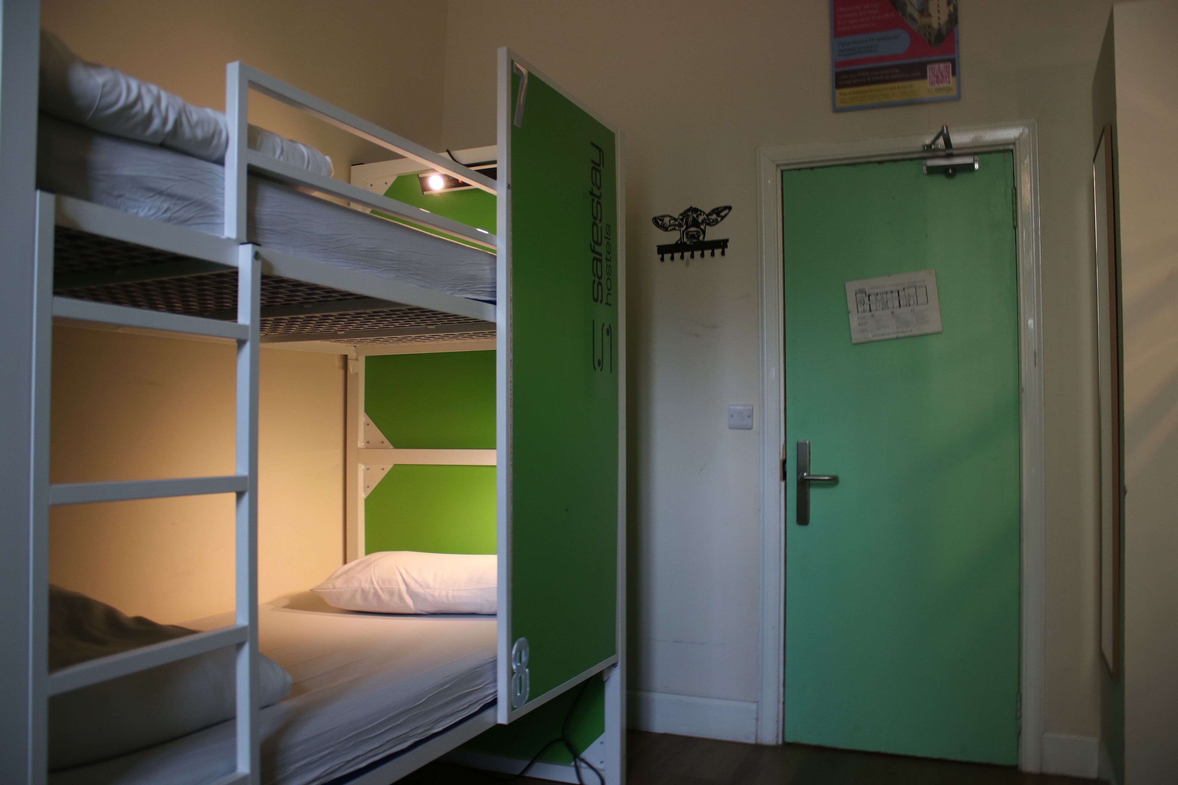 A bunk bed room with a green door and a sign on the wall.